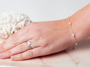 Vrouw met parel armband om pols en ring om vinger Bracelet Pearl Amaya & Ring Ginkgo Biloba 925 sterling zilver en zoetwaterparel Laura Design